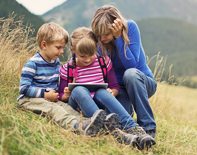 Un niño, una niña y una mujer viendo una tableta.